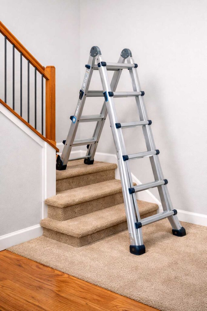 Homeowner using an articulating ladder on stairs to reach a high ceiling