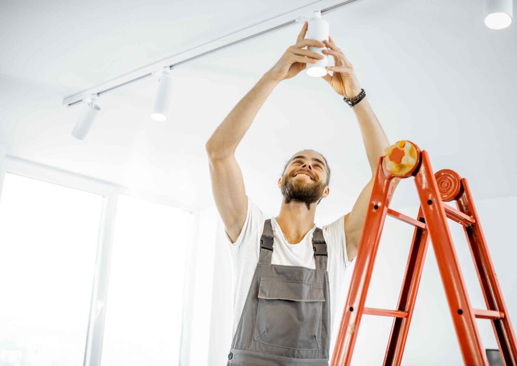 Homeowner safely installing a light fixture using a ladder