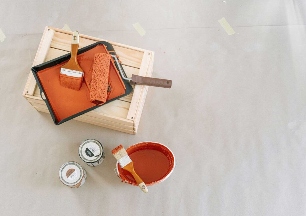 Tools and materials needed for exterior house painting including brushes, rollers, ladder, and paint