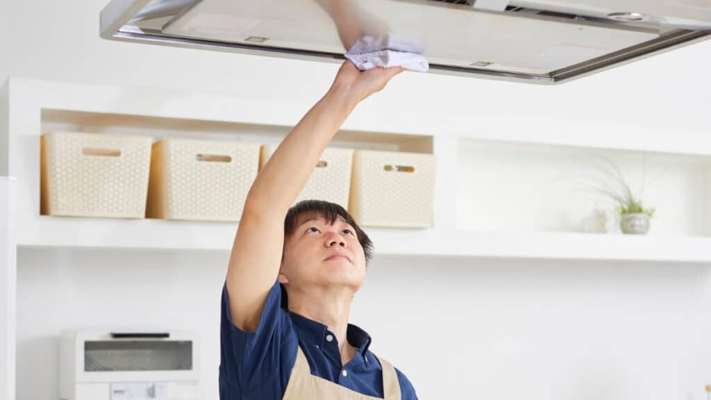 Wiping stainless steel stove hood in direction of grain with microfiber cloth