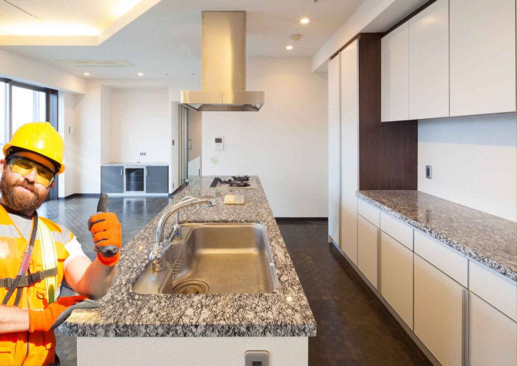 Professional installer placing granite countertop on kitchen island.