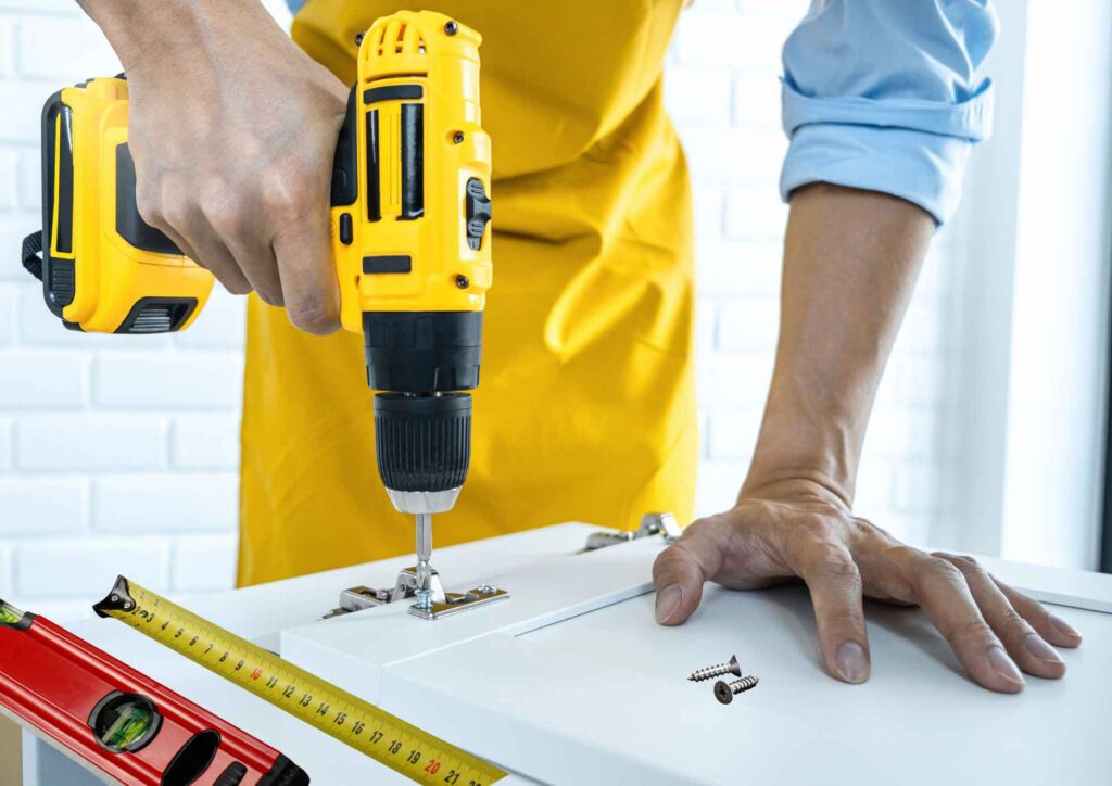 Tools and materials for installing kitchen cabinets, including a drill, tape measure, and level.