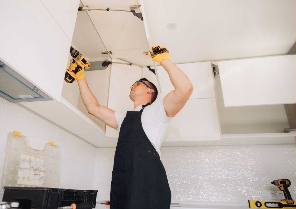 Professional installer working on installing prefab kitchen cabinets.