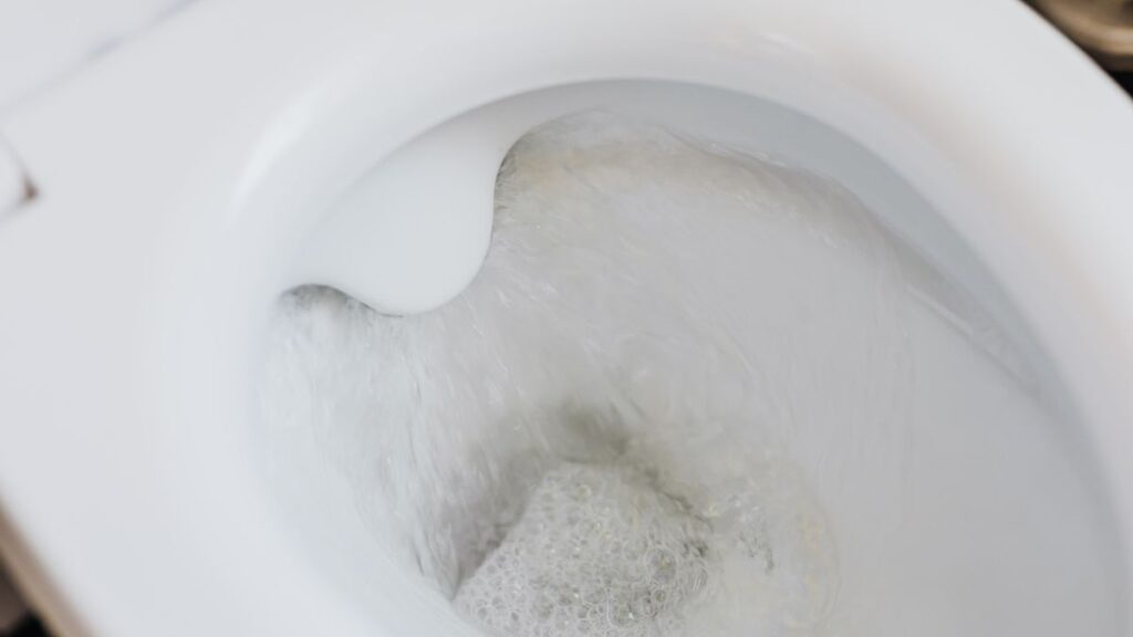 Baking soda and vinegar fizzing inside a toilet bowl during cleaning