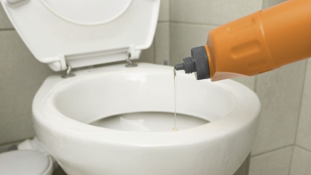 Pouring vinegar and baking soda into toilet bowl for cleaning