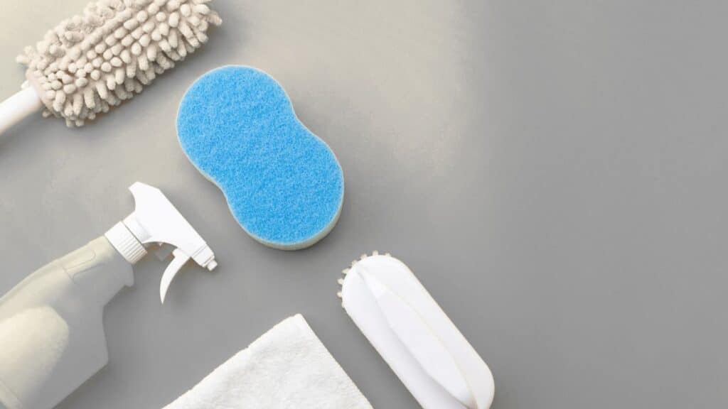 Microfiber cloths, bucket, dish soap, baking soda, and non-scratch scrub pad for cleaning kitchen cabinets