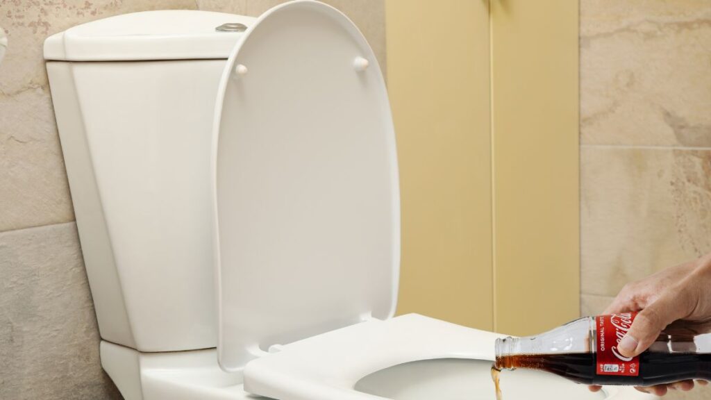 pouring Coca Cola into toilet bowl for cleaning