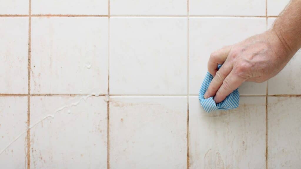 foam cleaner applied on shower tiles removing heavy soap scum buildup