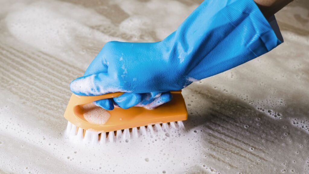 Scrubbing shower tile with non scratch brush after vinegar cleaning solution