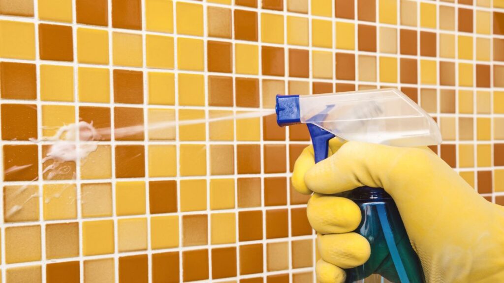 Applying vinegar and Dawn cleaning solution to shower wall to remove soap scum