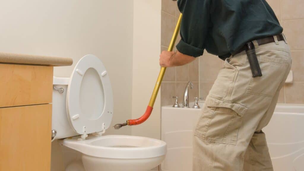 toilet auger inserted into toilet trap to remove blockage
