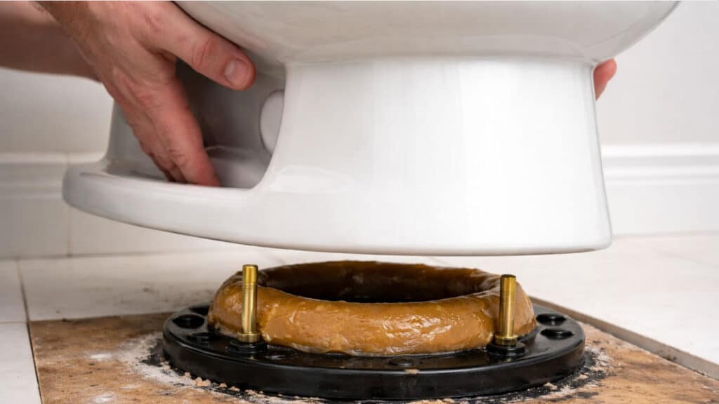 Toilet being reset onto flange with new wax ring installed