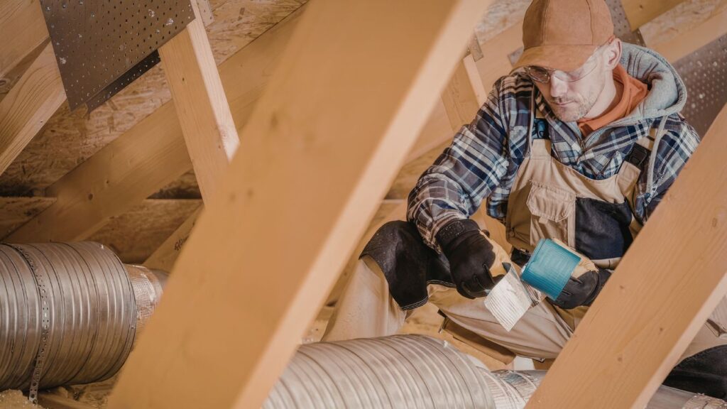 professional inspecting bathroom exhaust fan ductwork in attic